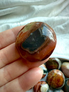 Polychrome Jasper mini palm stone with rich rust red and sage green coloring, polished smooth and held between fingers