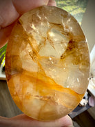 Golden Healer Quartz crystal bowl held in hand, small healing ring dish with luminous golden streaks