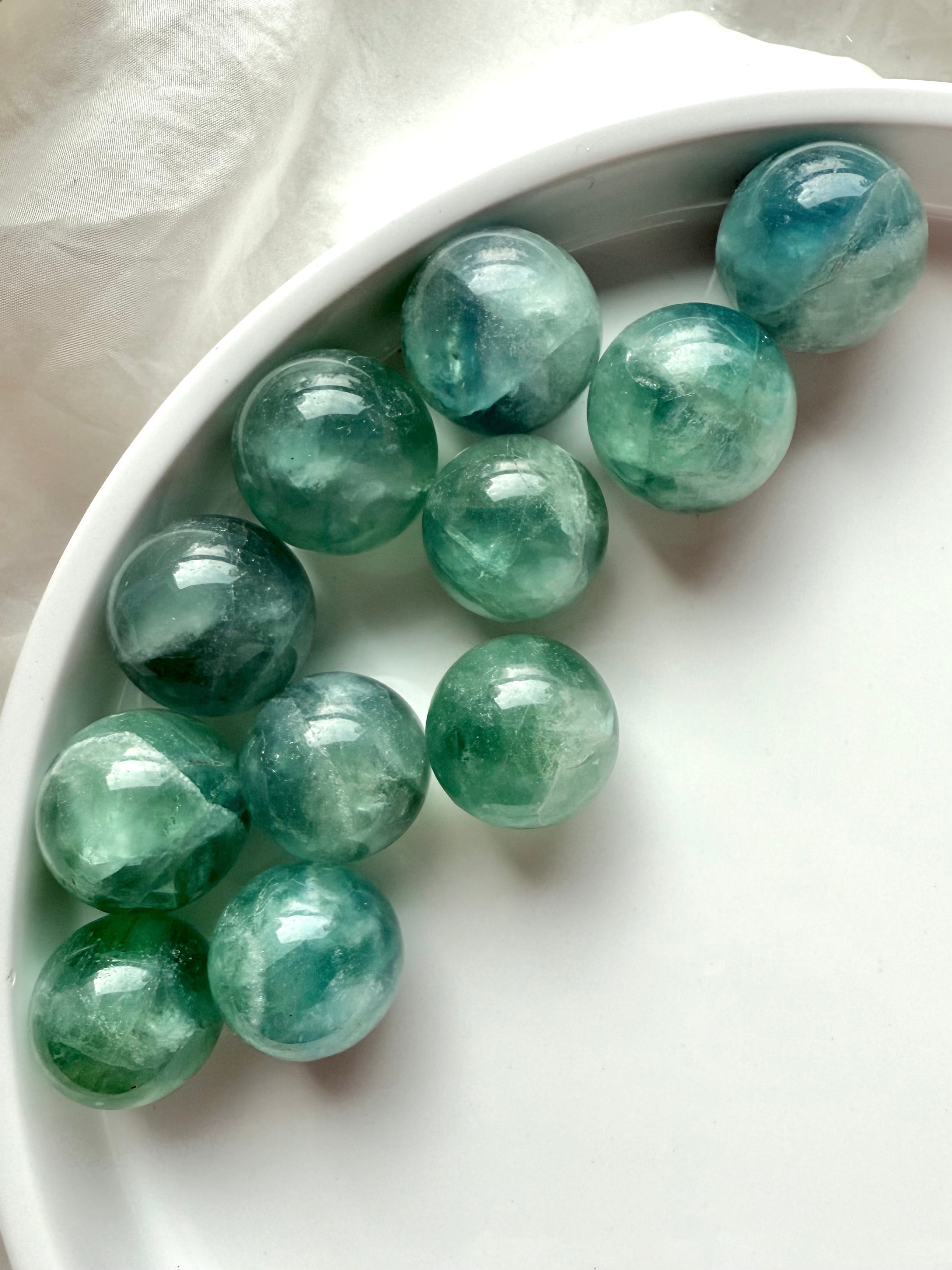 Group of mini teal Fluorite spheres with shimmering aqua tones, polished healing crystals for meditation and energy balance.