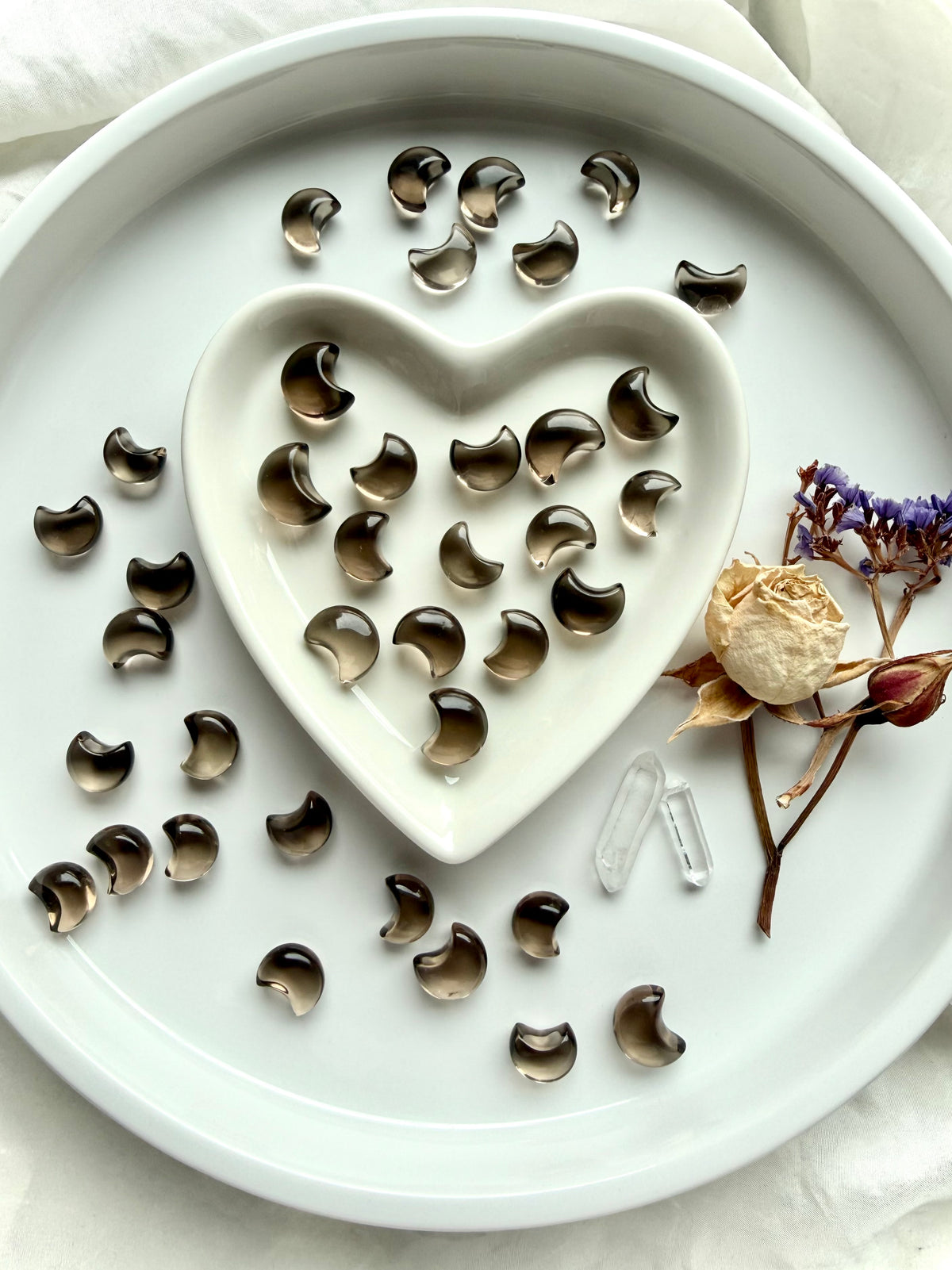 Mini Smoky Quartz moons arranged in a heart dish, celestial carvings showing their petite crescent shapes and smoky brown tones