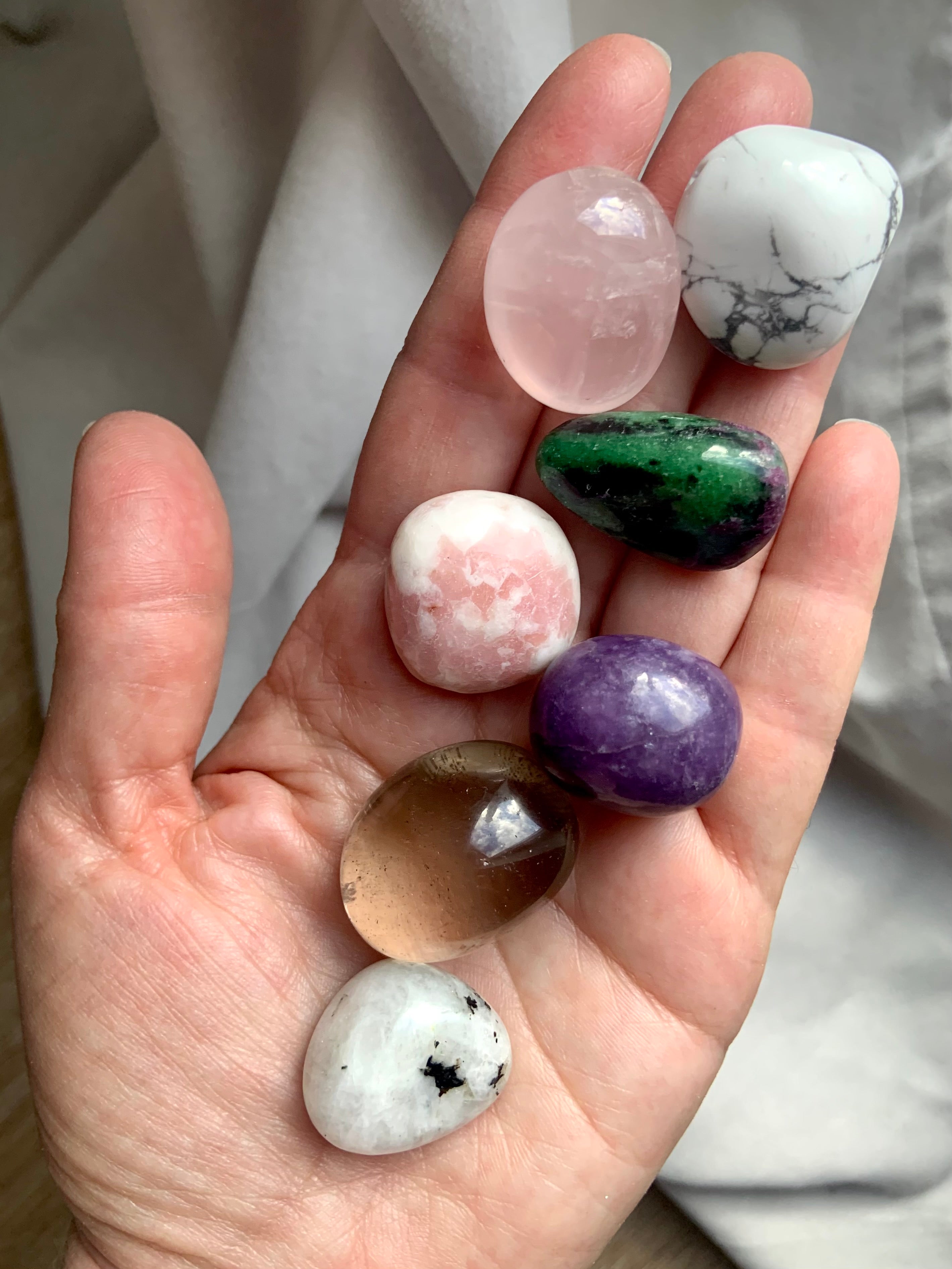 Grief support crystal set in my hand – includes rose quartz, smoky quartz, pink opal, moonstone, lepidolite, howlite & ruby zoisite