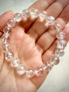 Clear Quartz crystal bracelet held in hand with transparent polished beads and light-catching flashes