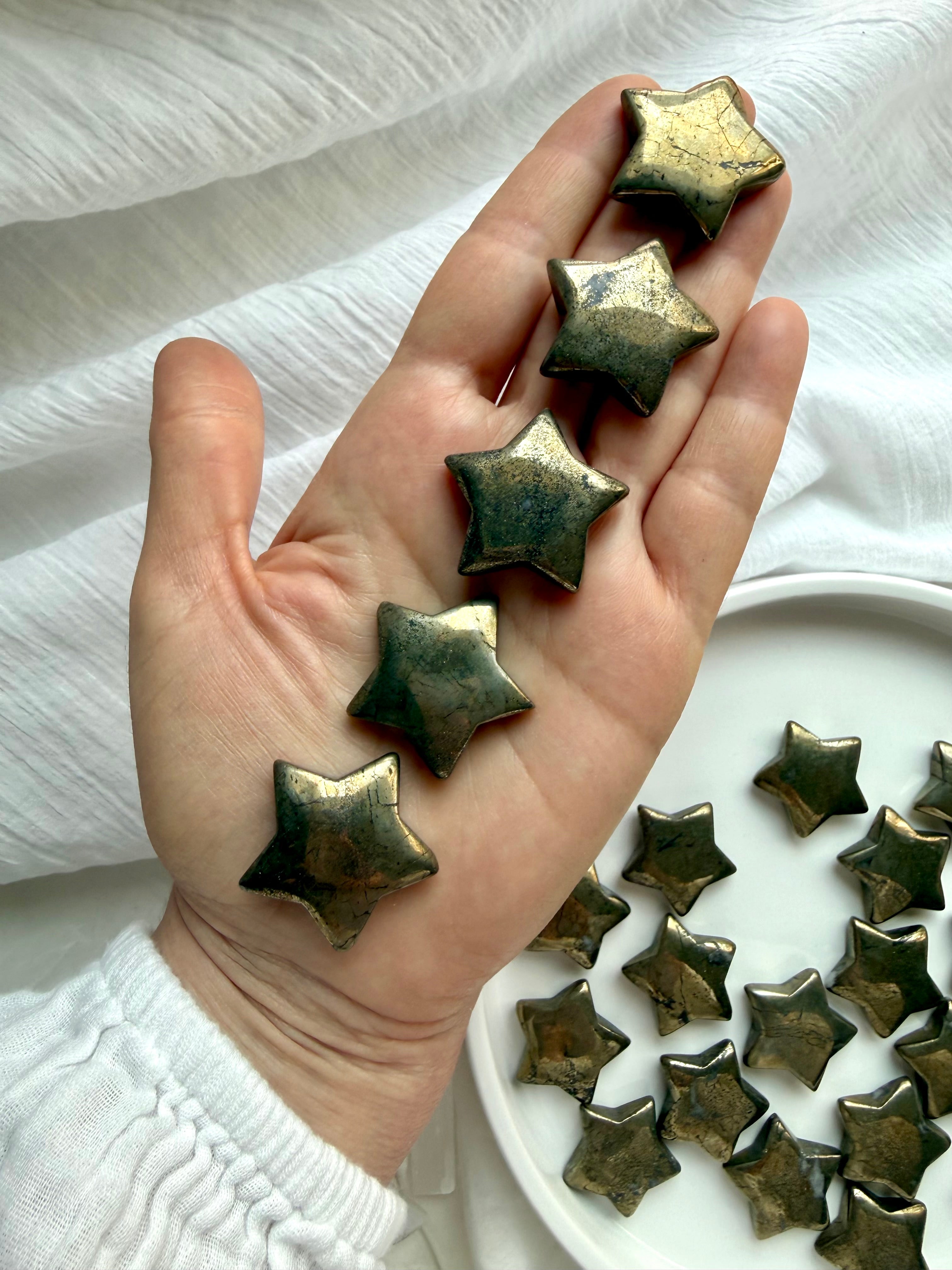 Pyrite stars held in hand showing natural golden metallic sheen and polished crystal finish