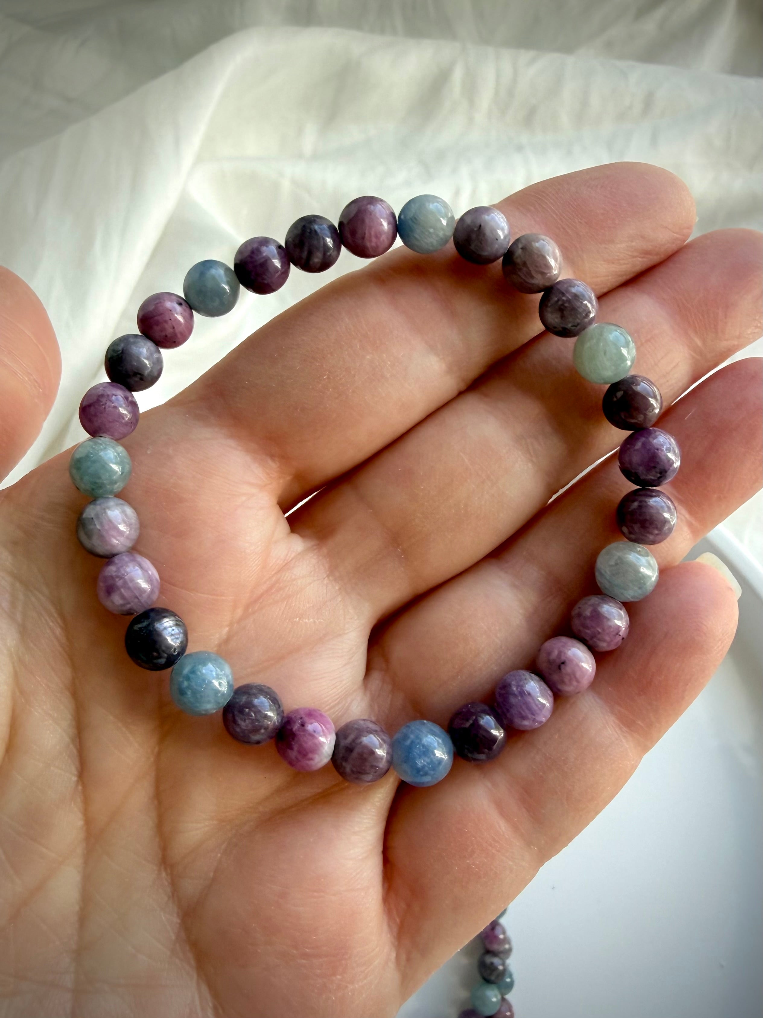 Ruby Sapphire crystal bracelet on hand showing the natural color variation of ruby & sapphire gemstone beads