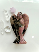 Rhodonite angel carving with soft pink tones and black matrix for heart healing and compassion