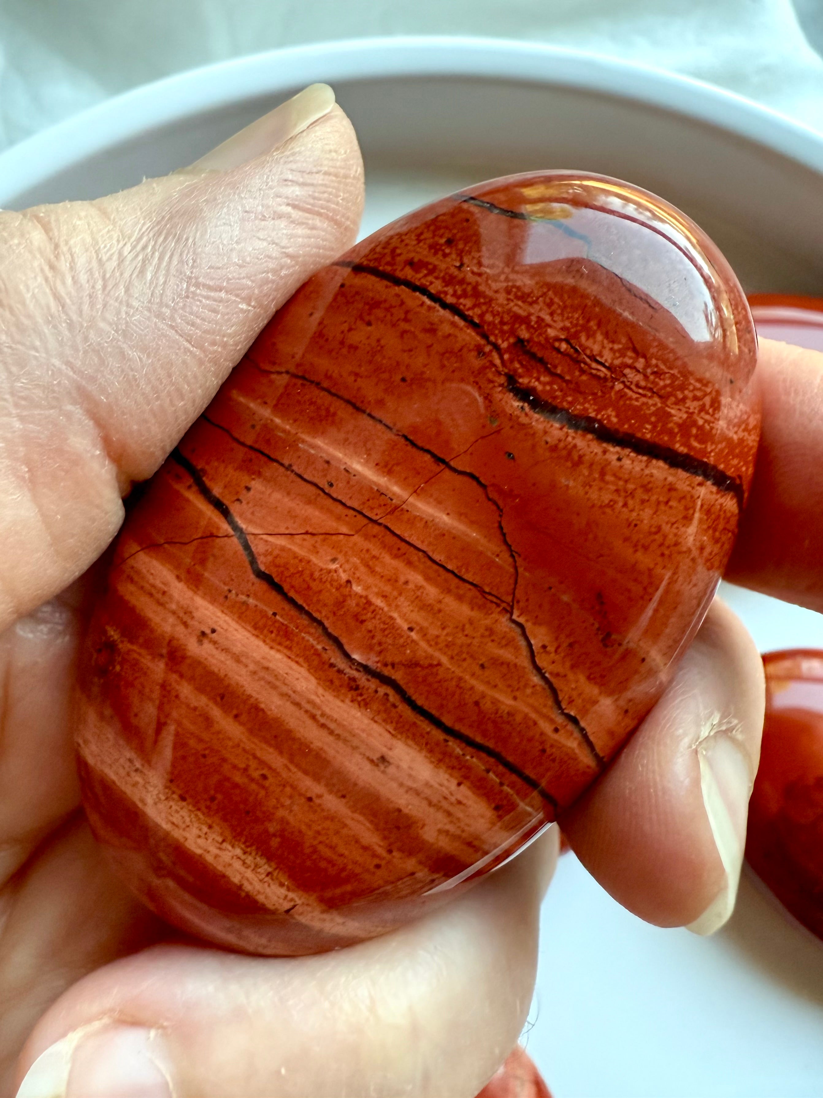 Macro shot of Red Jasper palm stone — grounding stone with rich red color and stabilizing energy.
