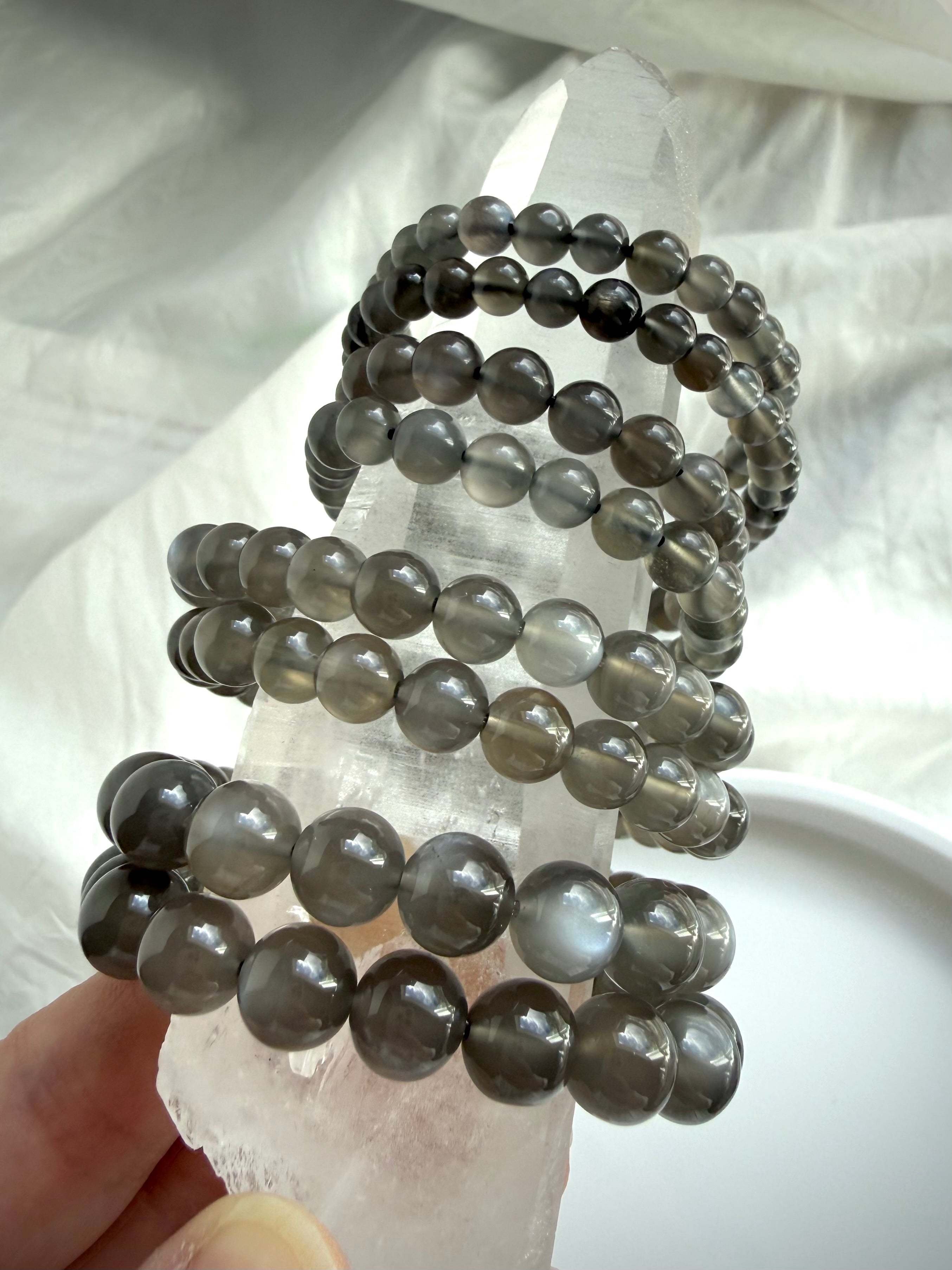 Black Moonstone bracelets displayed on Clear Quartz with silky adularescence and translucent inky charcoal gemstone beads
