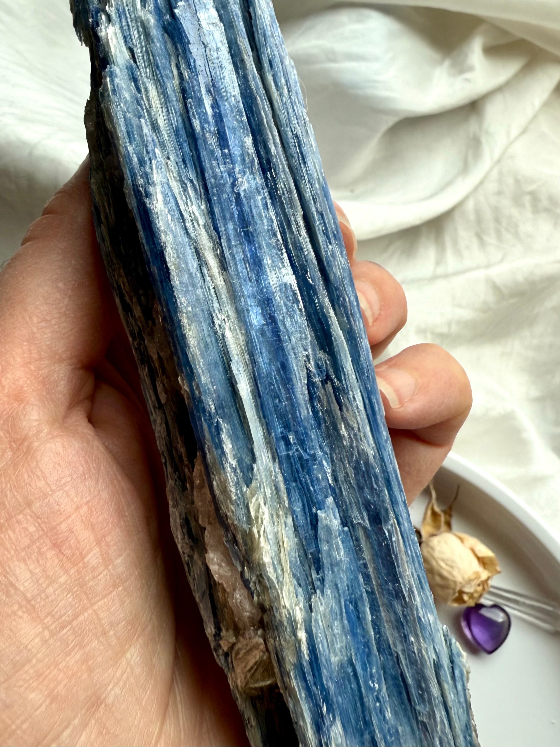 Macro close-up of blue kyanite crystal blades with quartz seam, shimmering muscovite + subtle black tourmaline inclusions, raw healing gemstone texture