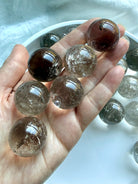 Handheld Smoky Quartz mini crystal spheres with rainbow inclusions and natural smoky transparency