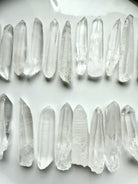 Two rows of Lemurian Seed Quartz Points on a white background showing clarity, striations & natural variety — powerful tools for spiritual awakening
