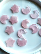 Overhead view of rose quartz crystal moons and stars on a white plate 