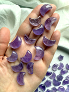 Hand holding small amethyst crescent moons showing size and smooth polish