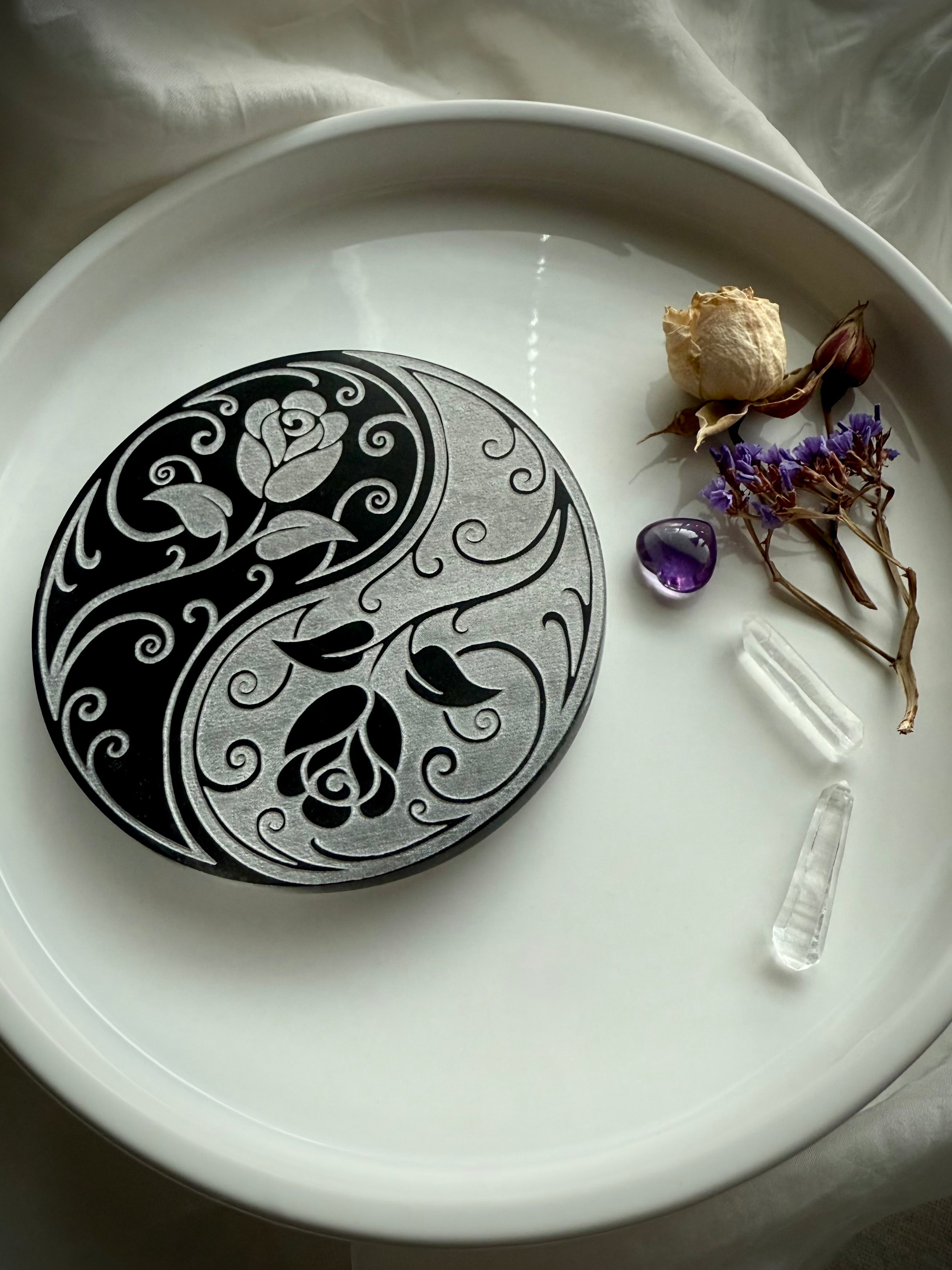 Round selenite charging plate with yin yang rose design styled with crystals and flowers for cleansing rituals