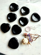 black sheen obsidian heart worry stones arranged together showing polished surface and reflective flash