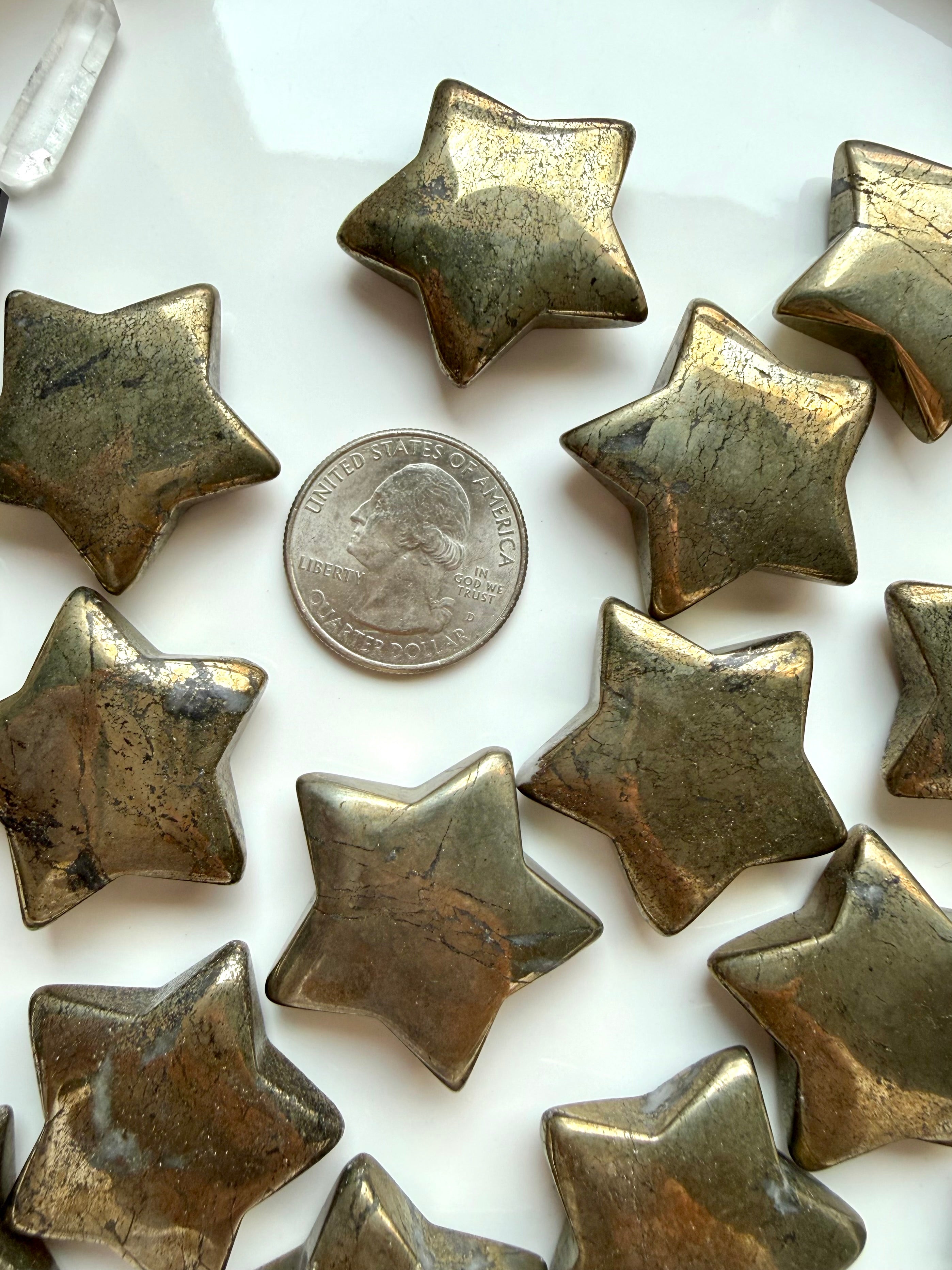 Pyrite star crystals shown with a US quarter for scale, with reflective gold surface & natural patterns