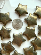 Pyrite star crystals shown with a US quarter for scale, with reflective gold surface & natural patterns