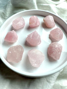 Medium raw Rose Quartz crystal chunks in soft pink hues on white plate 
