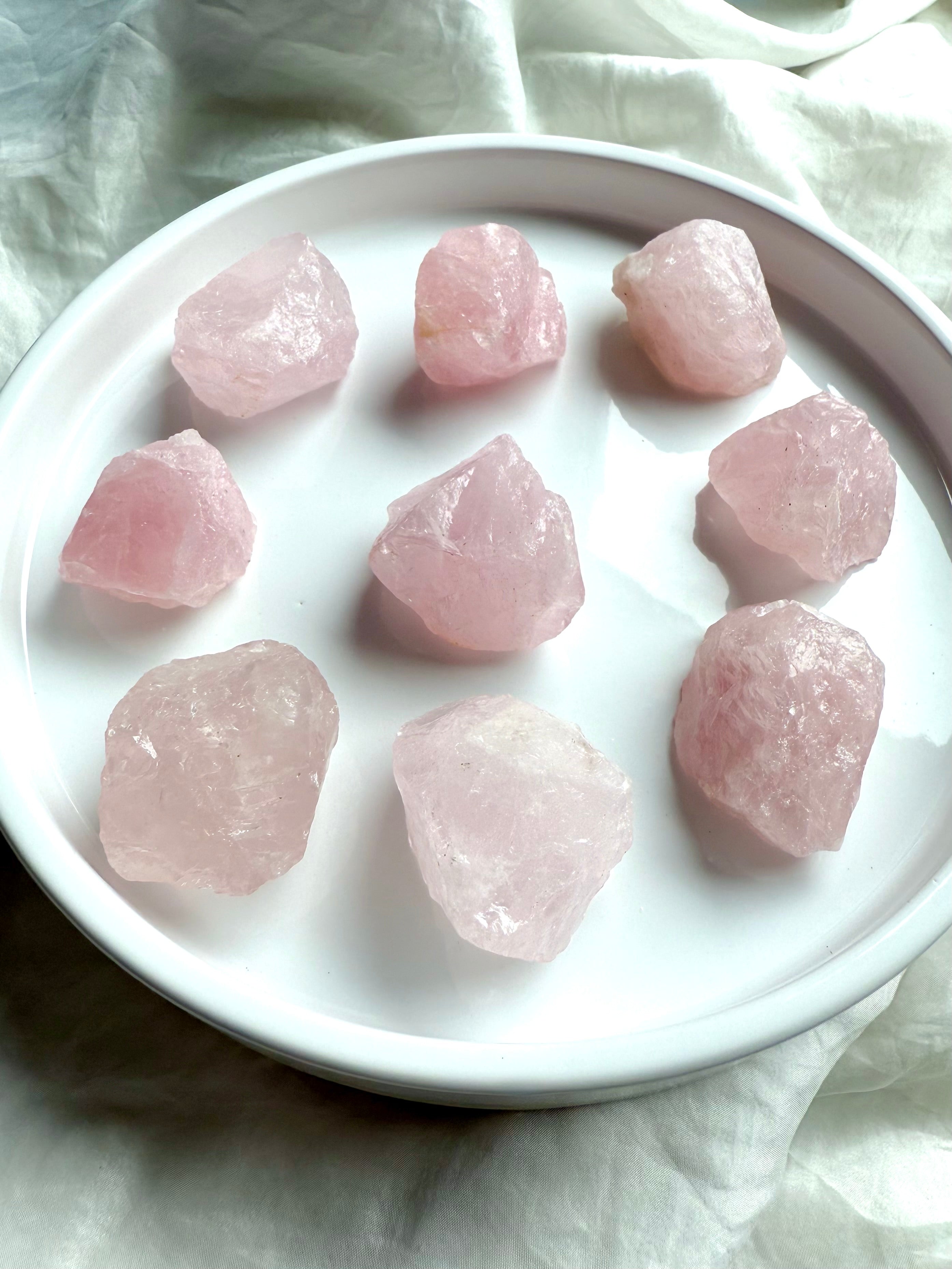Medium raw Rose Quartz crystal chunks in soft pink hues on white plate 