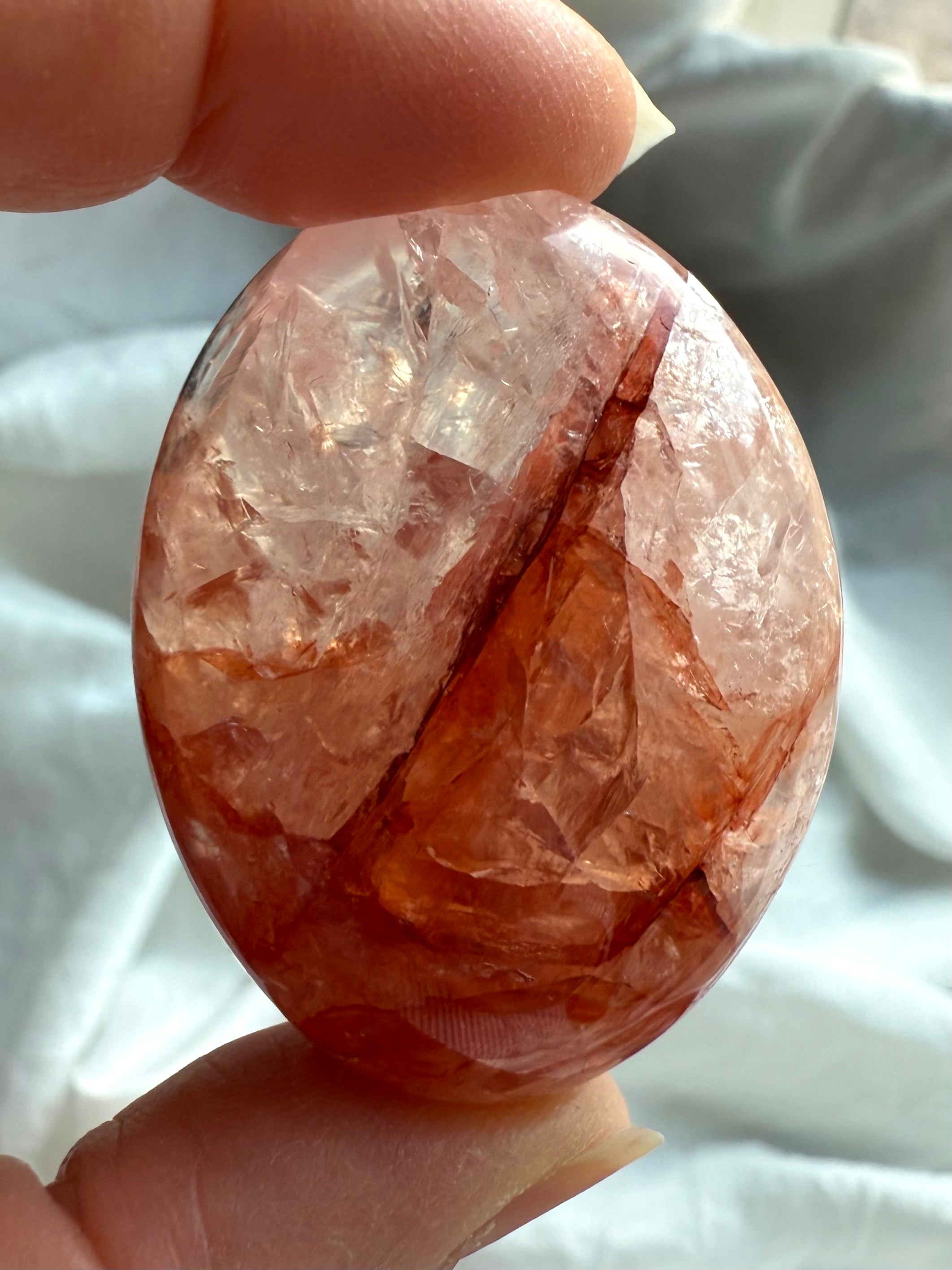 Closeup of Fire Quartz palm stone with fiery red inclusions and translucent quartz matrix