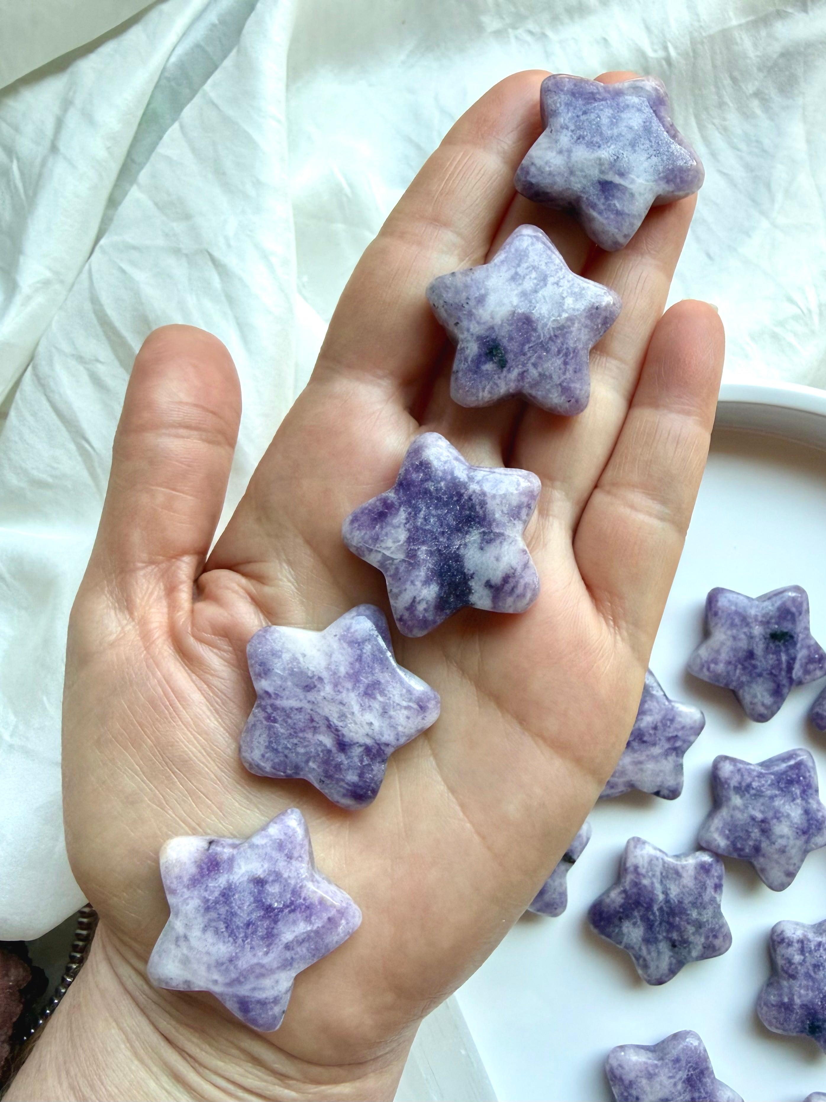 Lepidolite star crystal carvings held in hand with mottled purple patterning for calm, intuition and spiritual awareness