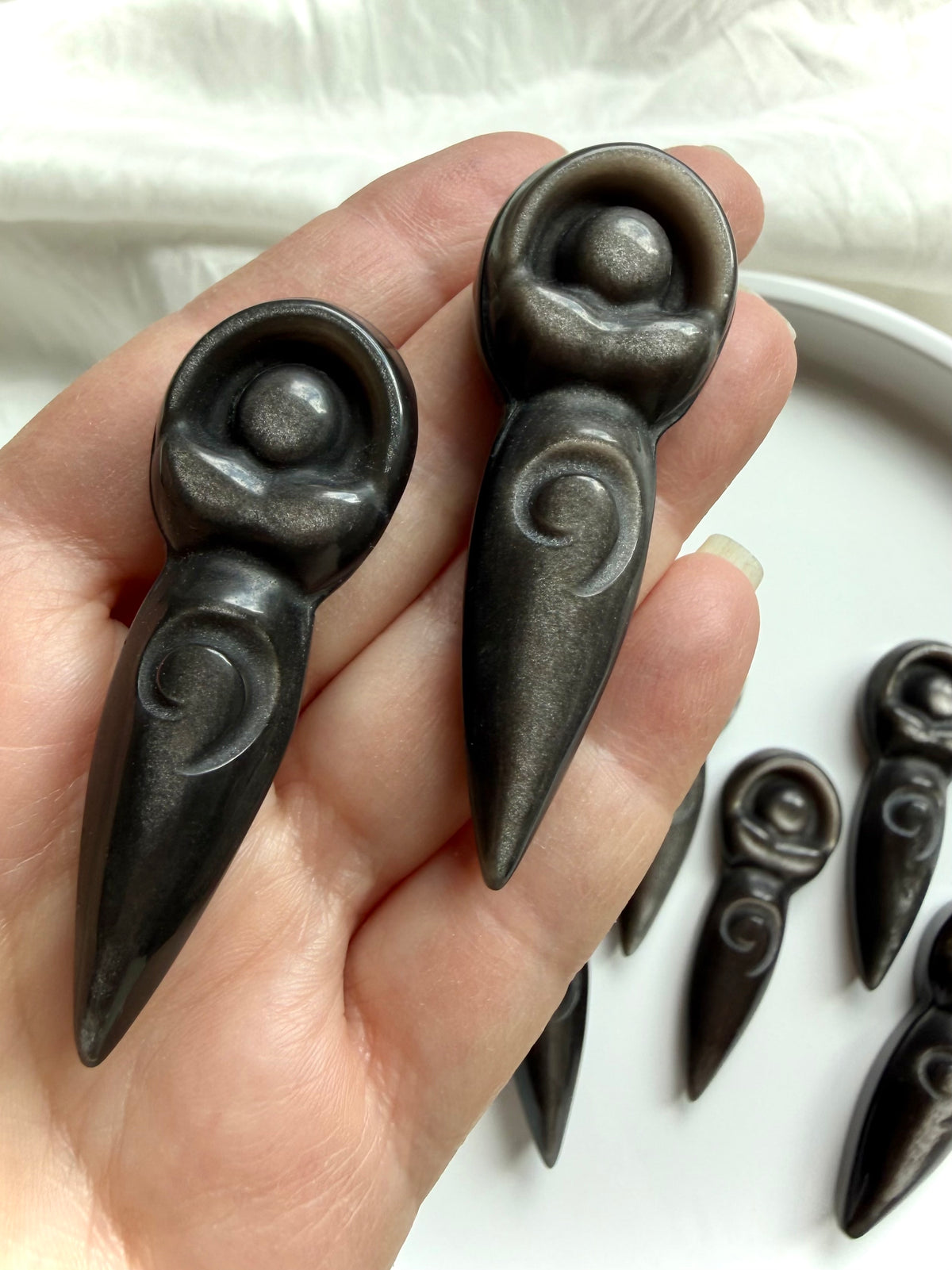 Silver Sheen Obsidian goddess carvings held in hand showing size, polished finish and natural silver sheen