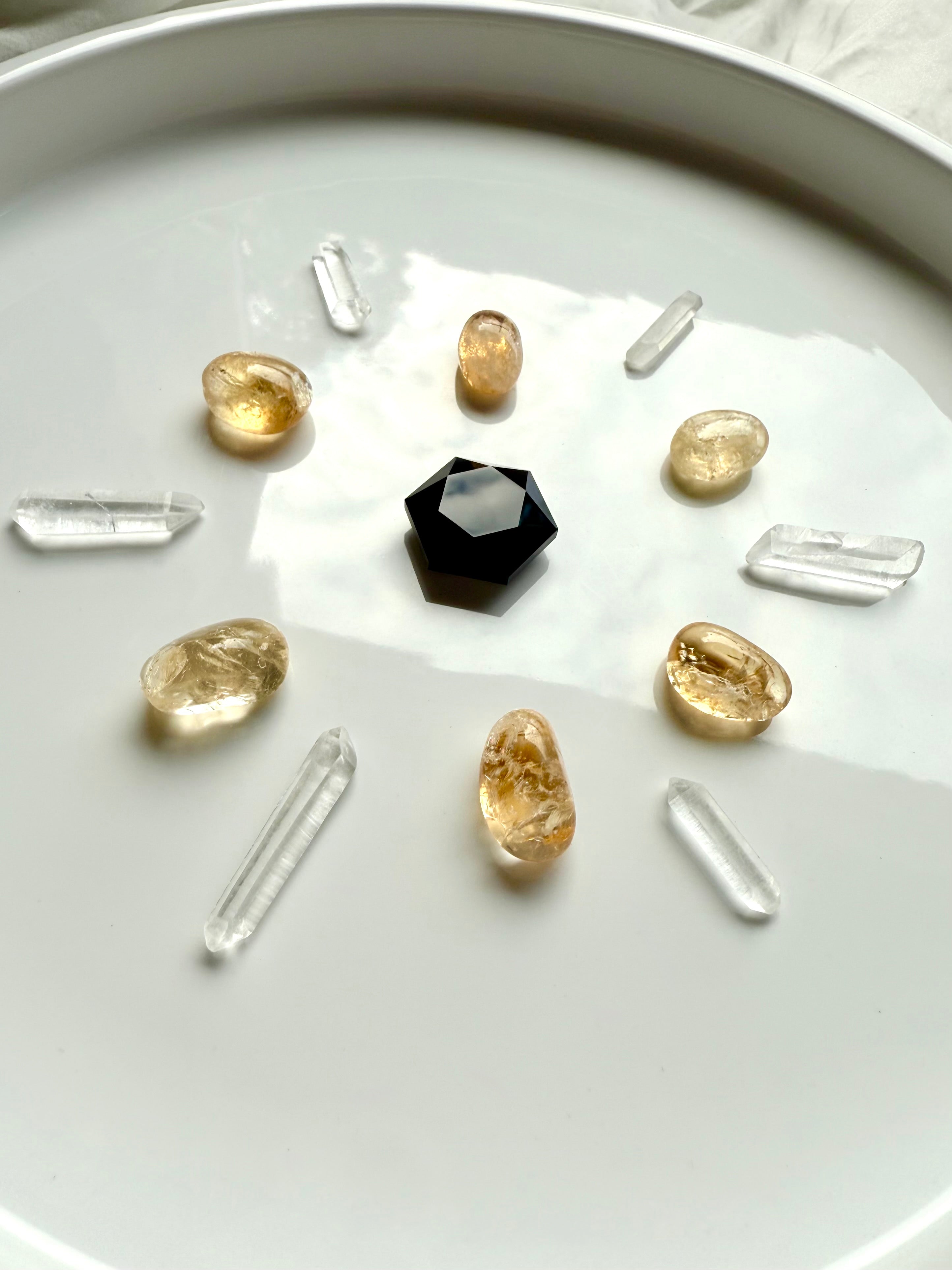 Crystal grid for protection with faceted Black Obsidian hexagon in center, surrounded by citrine tumbles and clear quartz points radiating outward