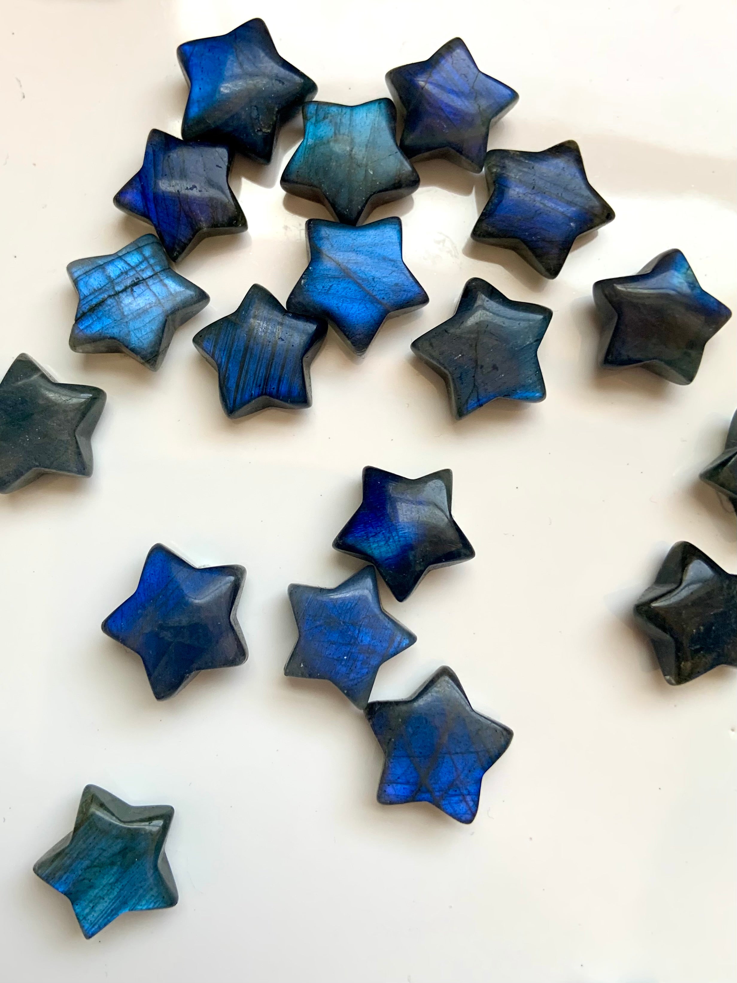 Close-up of deep blue flash Labradorite crystal stars on white — mini star carvings for intuition, Third Eye chakra activation &amp; spiritual protection.