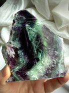 Polished fluorite slab photographed in natural light highlighting layered green and violet color zoning with rainbows