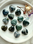 Moss Agate hearts with forest-green moss patterns and translucent quartz, arranged on a white tray