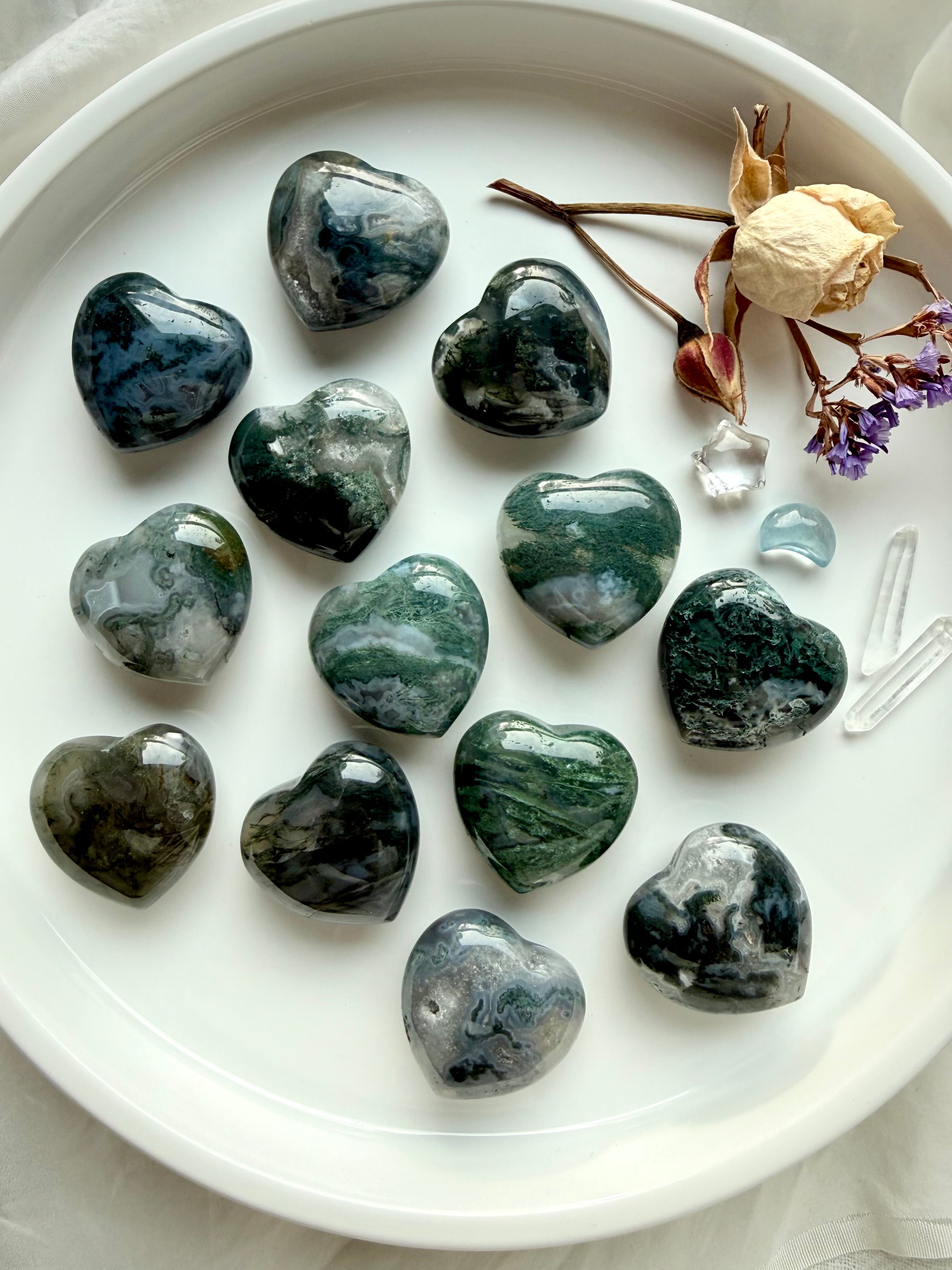 Moss Agate hearts with forest-green moss patterns and translucent quartz, arranged on a white tray