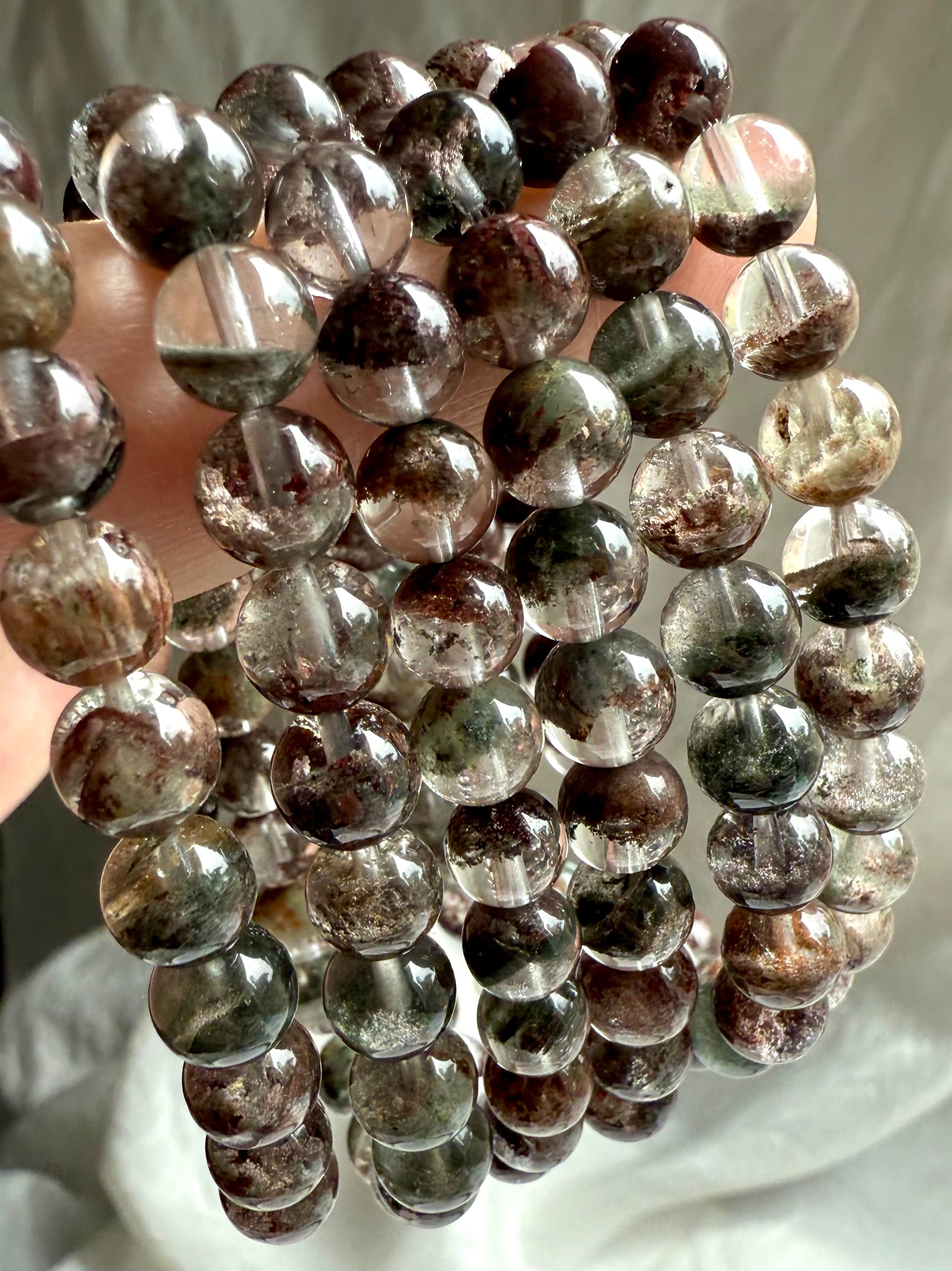 Detailed view of round Garden Quartz beads showing red, green, and brown chlorite phantoms