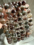 Detailed view of round Garden Quartz beads showing red, green, and brown chlorite phantoms