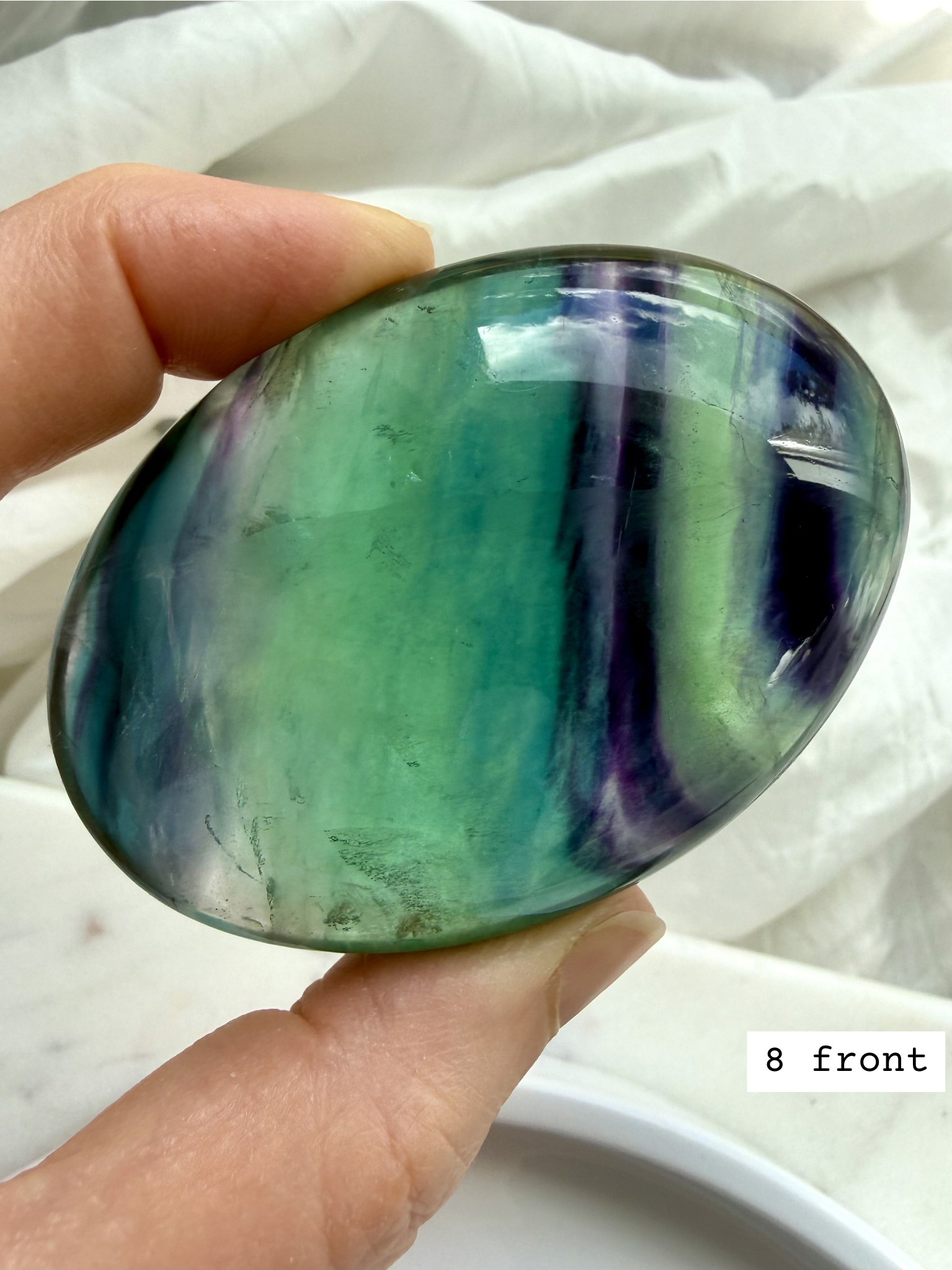 Teal fluorite palm stone #8 front view featuring bold blue green banding and polished oval shape