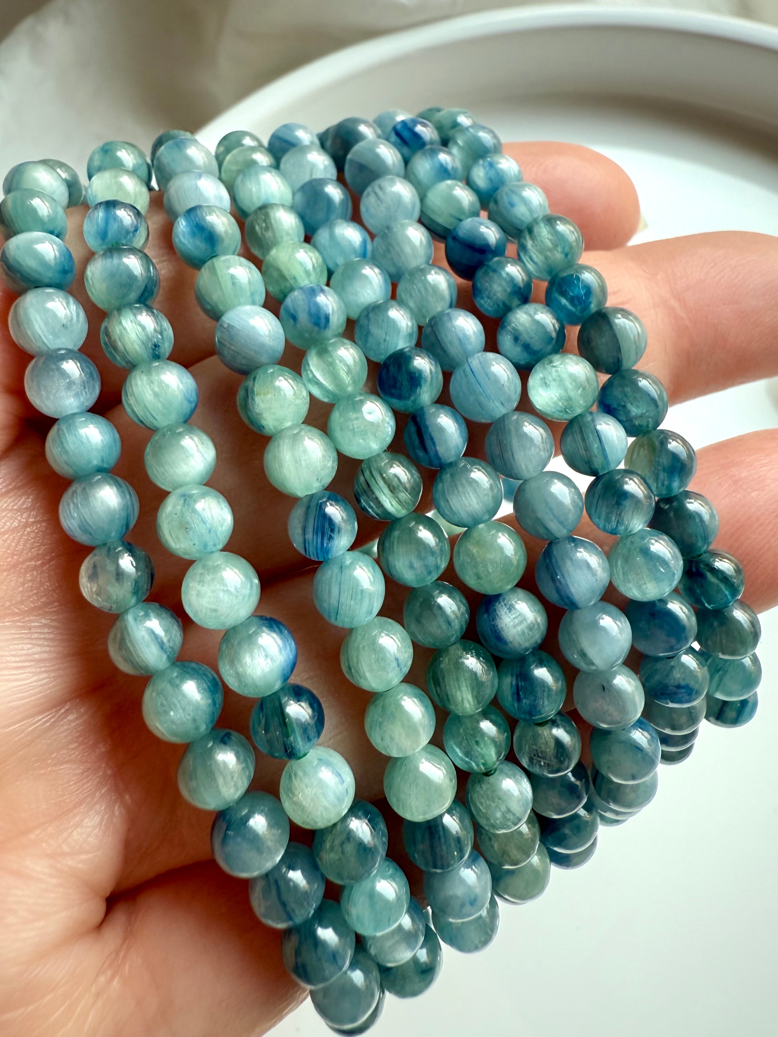 crystal bracelets arranged on hand with luminous banded blue-green kyanite beads for clarity and energy flow