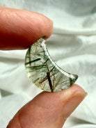 Green Tourmaline Quartz crescent moon held in hand with dense needle-like inclusions and translucent polished quartz