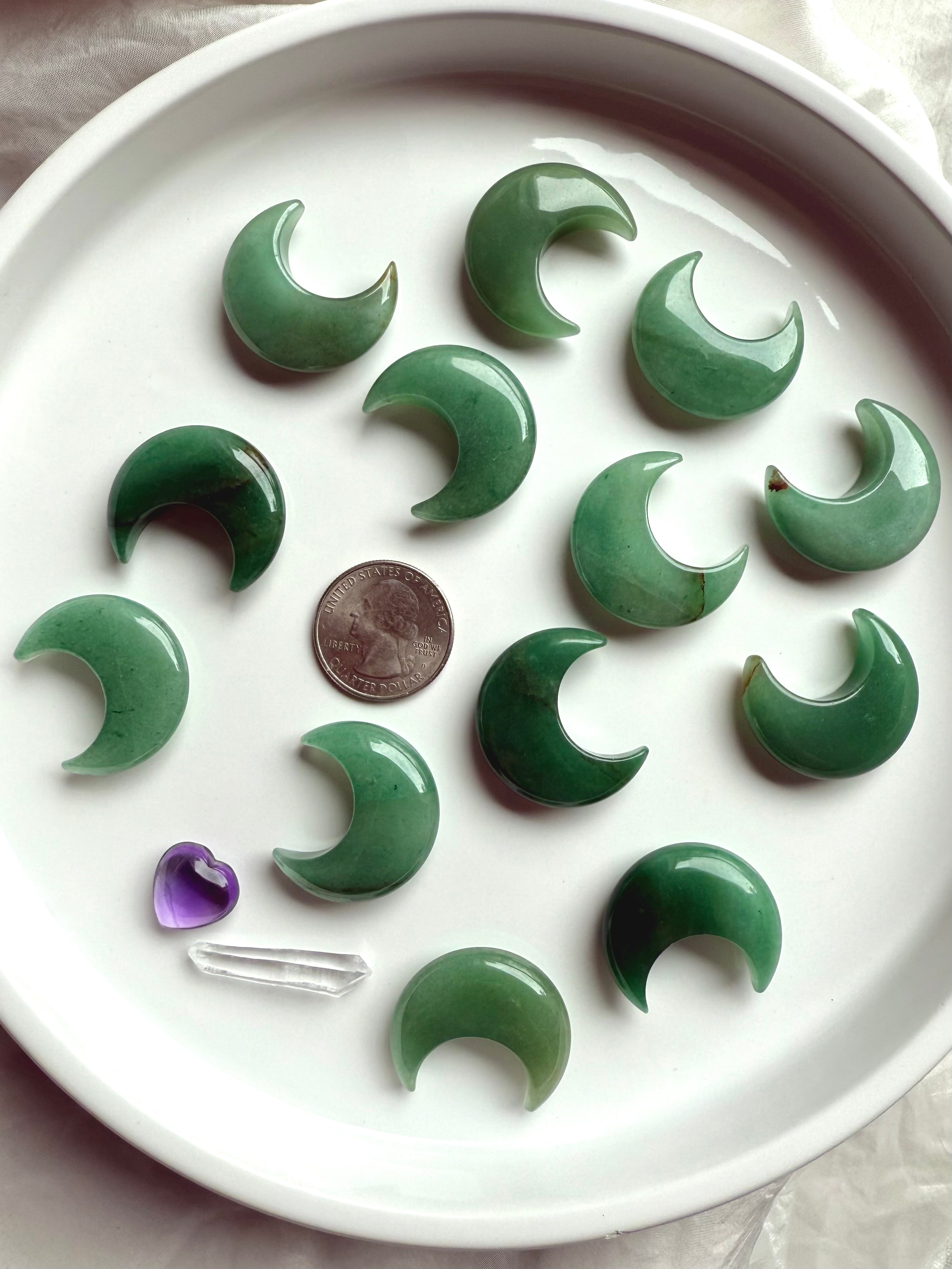 Flatlay of Green Aventurine moons on white plate with quarter for scale, crystal carvings for altar décor and meditation