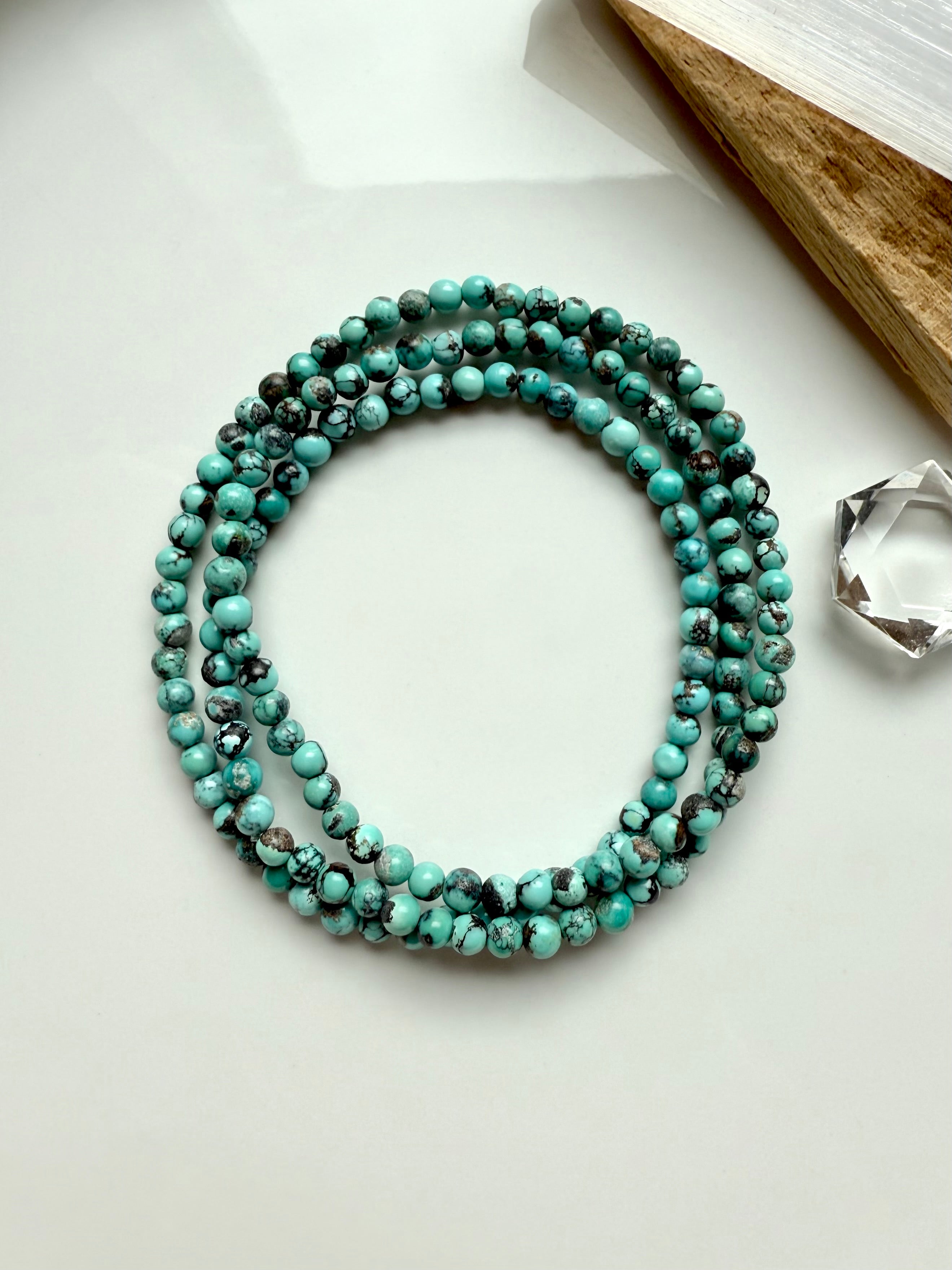 Natural Chinese Turquoise gemstone wrap bracelet laid in a circle on white background with earthy matrix and soft sage green tones