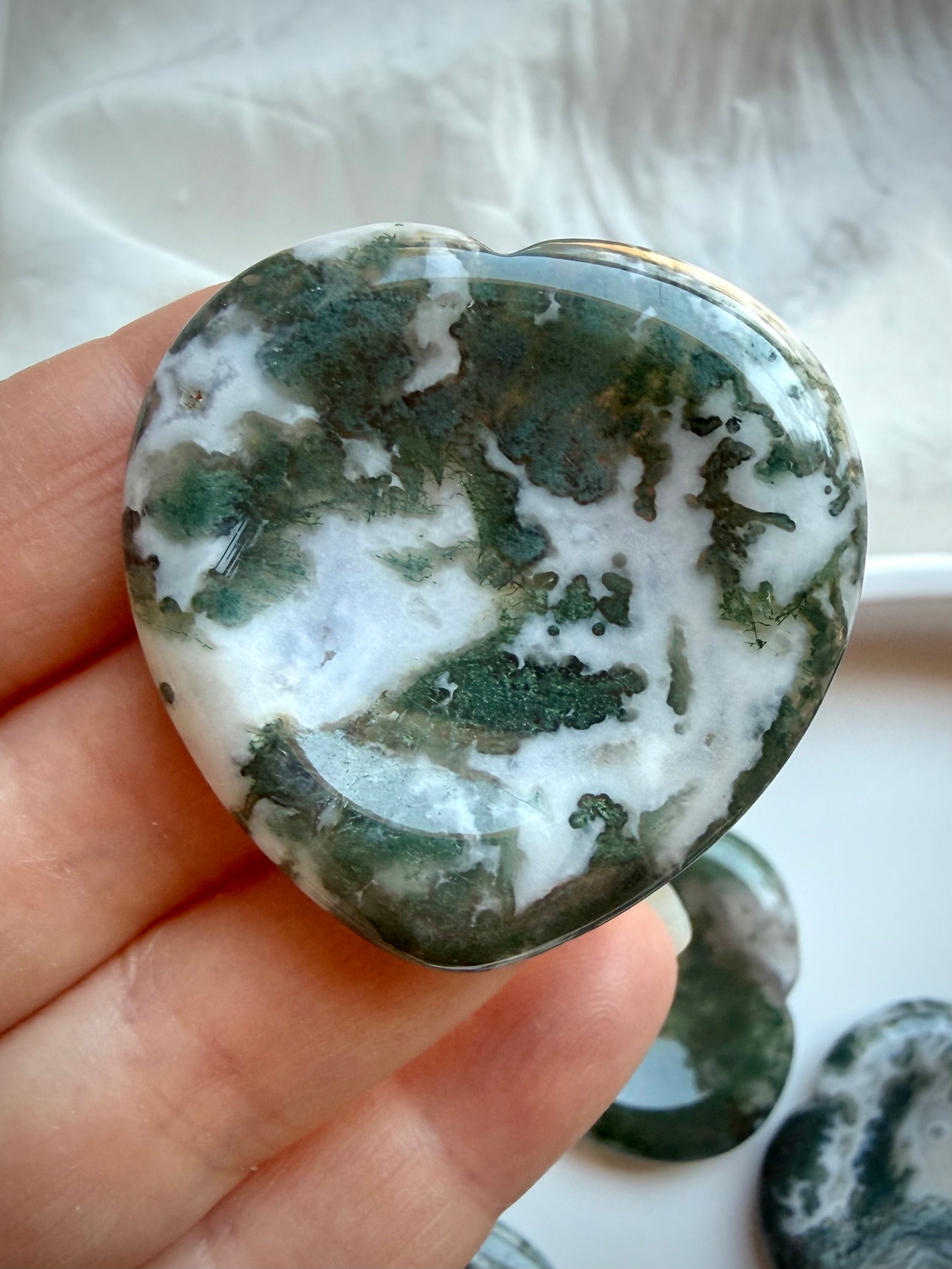 Large Moss Agate heart worry stone held in hand with white quartz and green landscape patterns