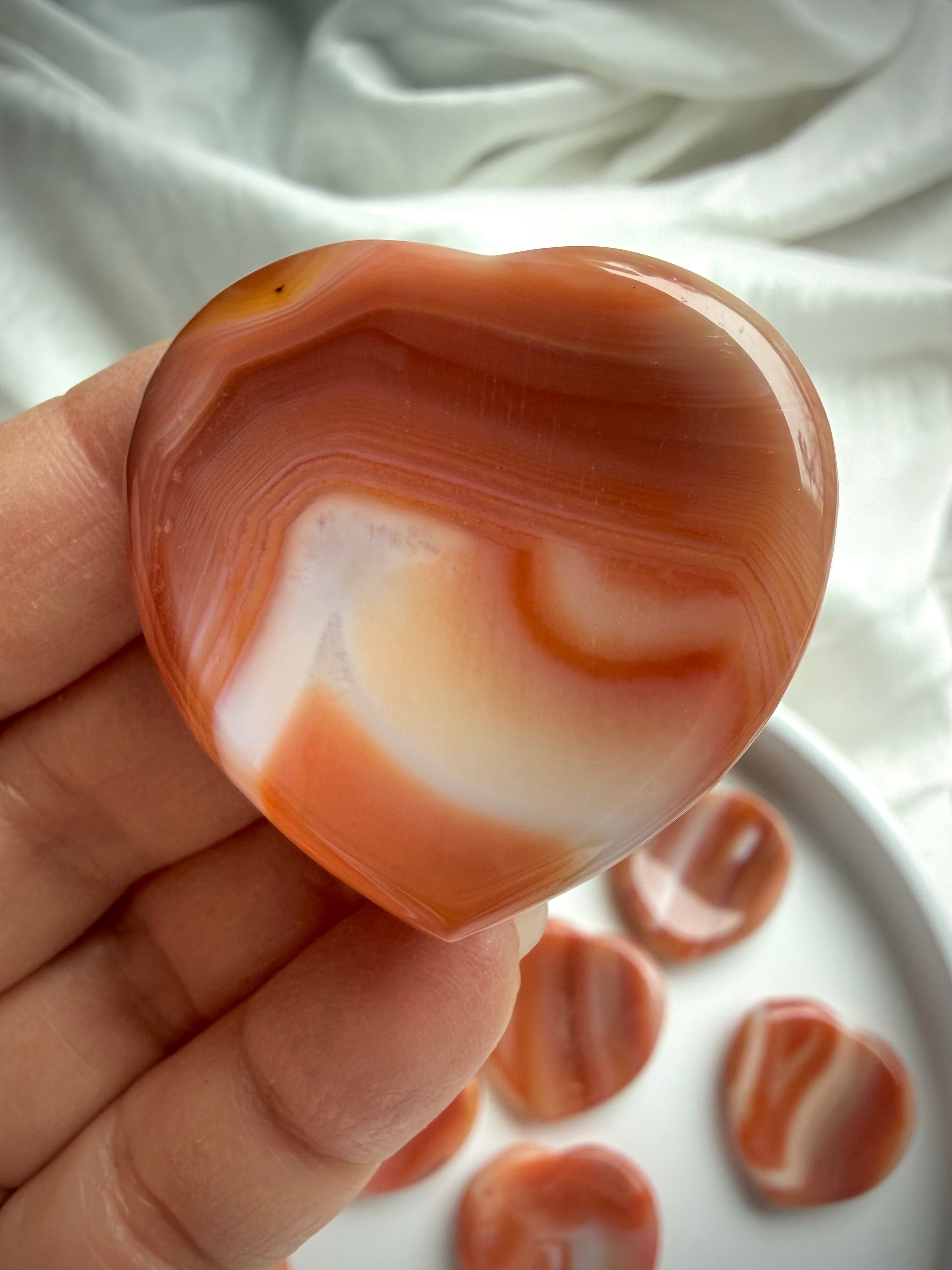 Carnelian heart worry stone crystal held in hand for grounding, courage, and Sacral Chakra energy