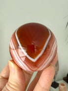 A stunning banded carnelian sphere with an intricate chevron pattern
