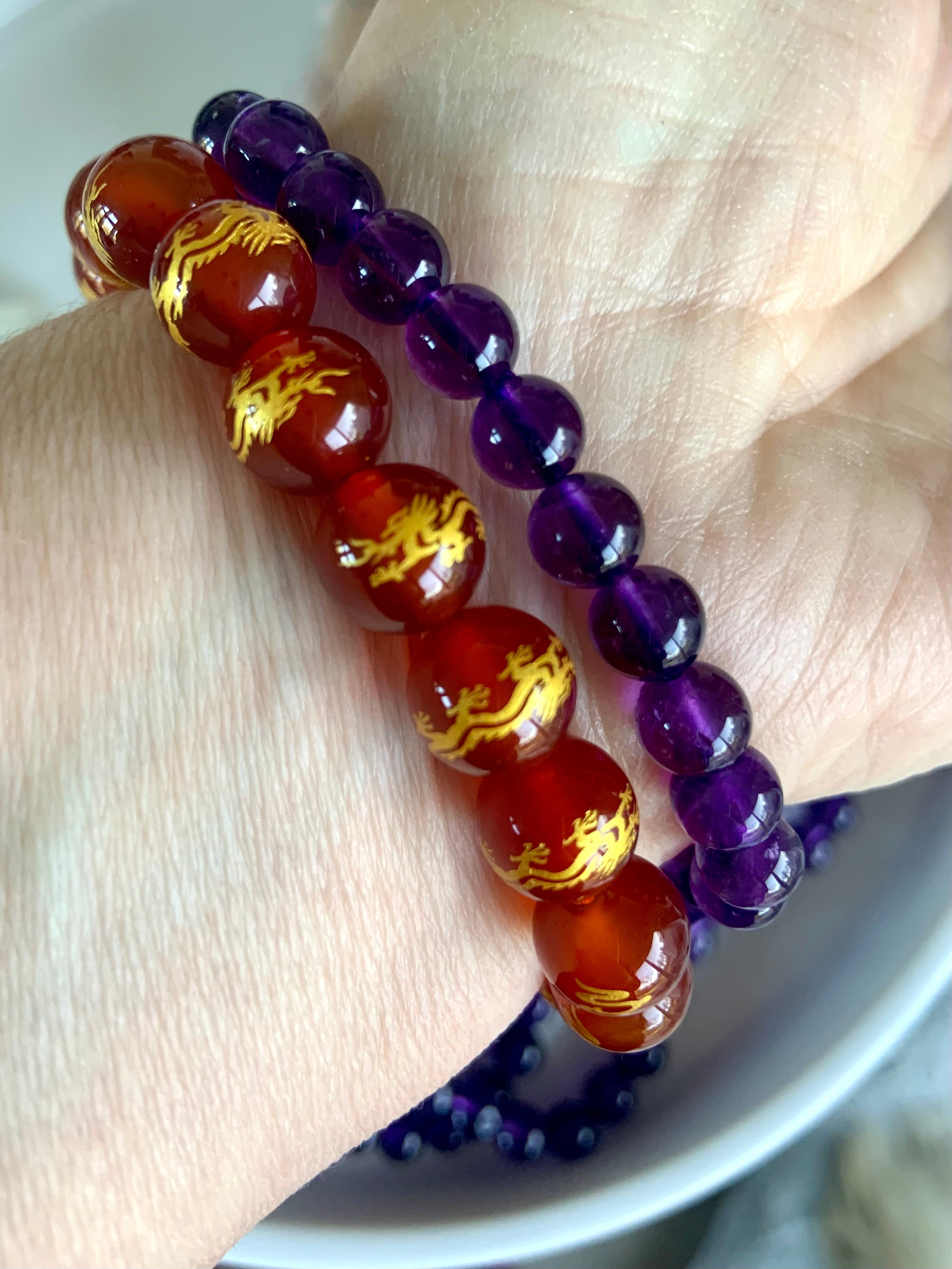 An amethyst bracelet worn with a carnelian bracelet with gold dragon beads