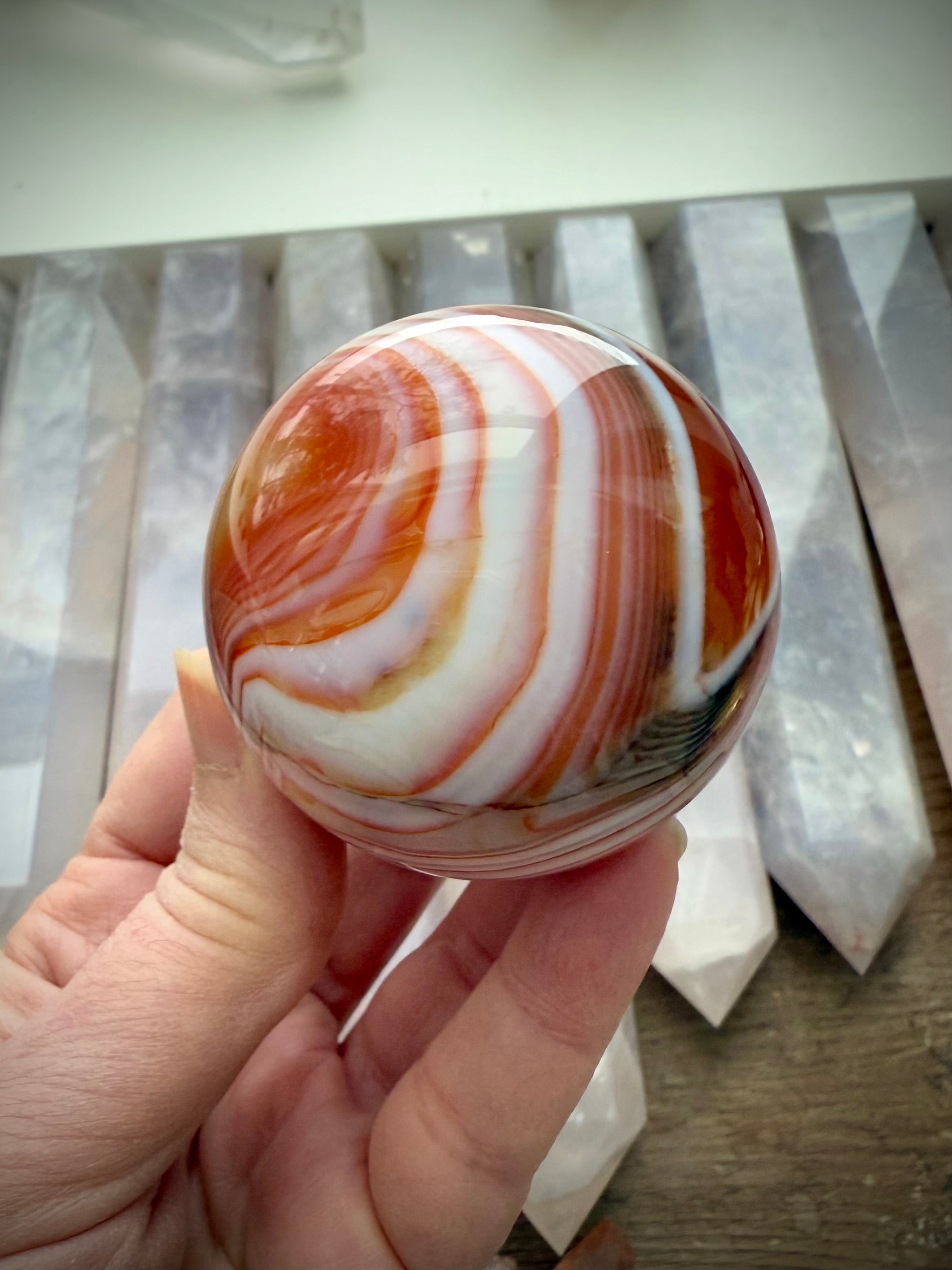 A stunning carnelian sphere with vibrant reddish orange colors + contrasting white banding