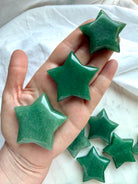 Green Aventurine crystal stars held in hand showing size variation, glossy polish, and naturally varied green color