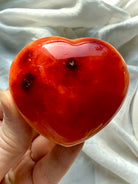 Palm size Carnelian heart crystal glowing in warm red-orange hues, polished healing stone for creativity and confidence