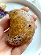 peachy yellow ocean jasper moon with detailed orbicular markings displayed in hand, a nurturing crystal for emotional healing and heart-centered support