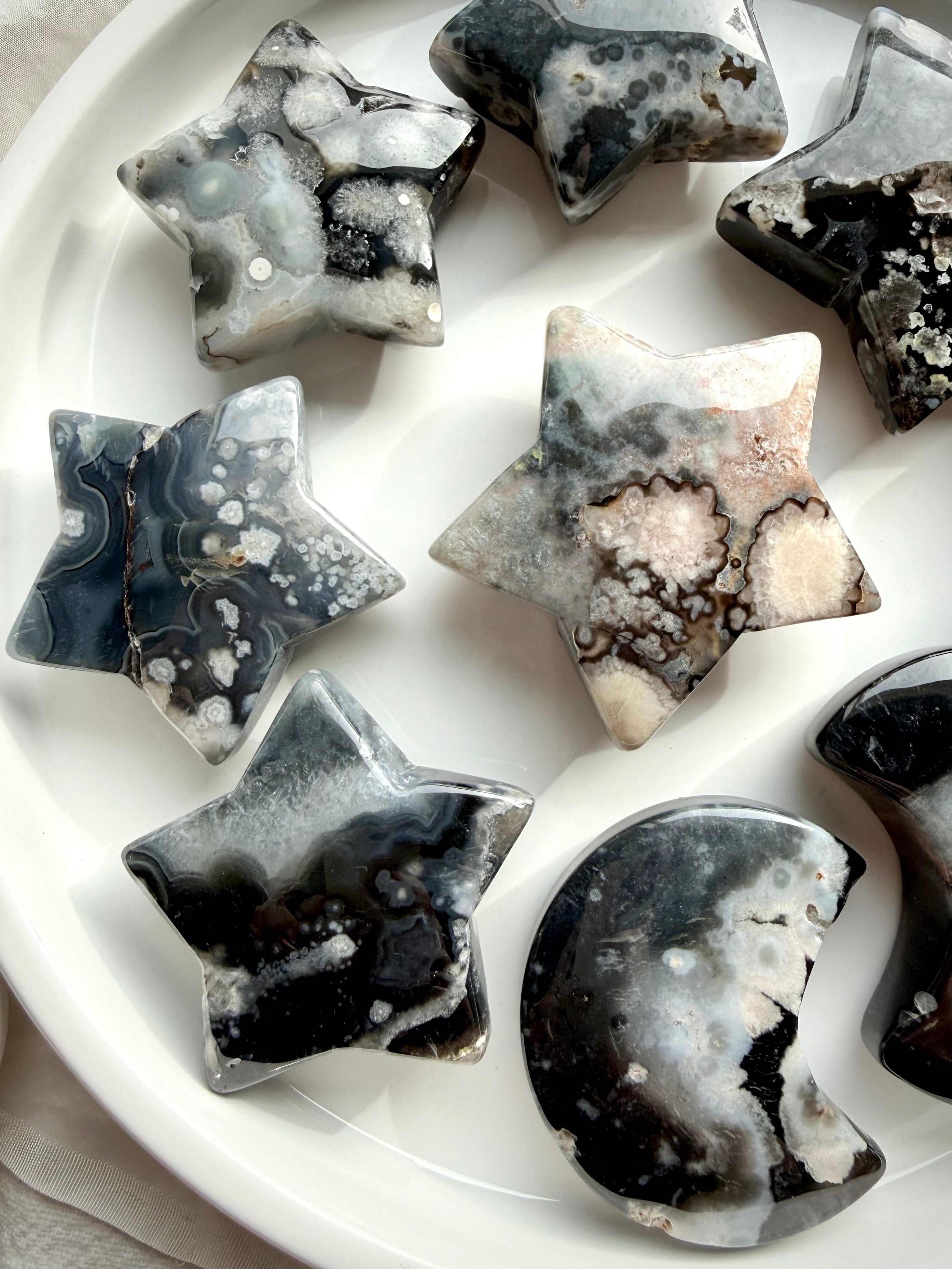 black flower agate moon and star carvings set on dish showing full assortment with natural floral plume patterns