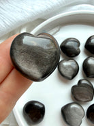 Silver Sheen Obsidian heart held in hand showing smoky charcoal color and reflective silver sheen