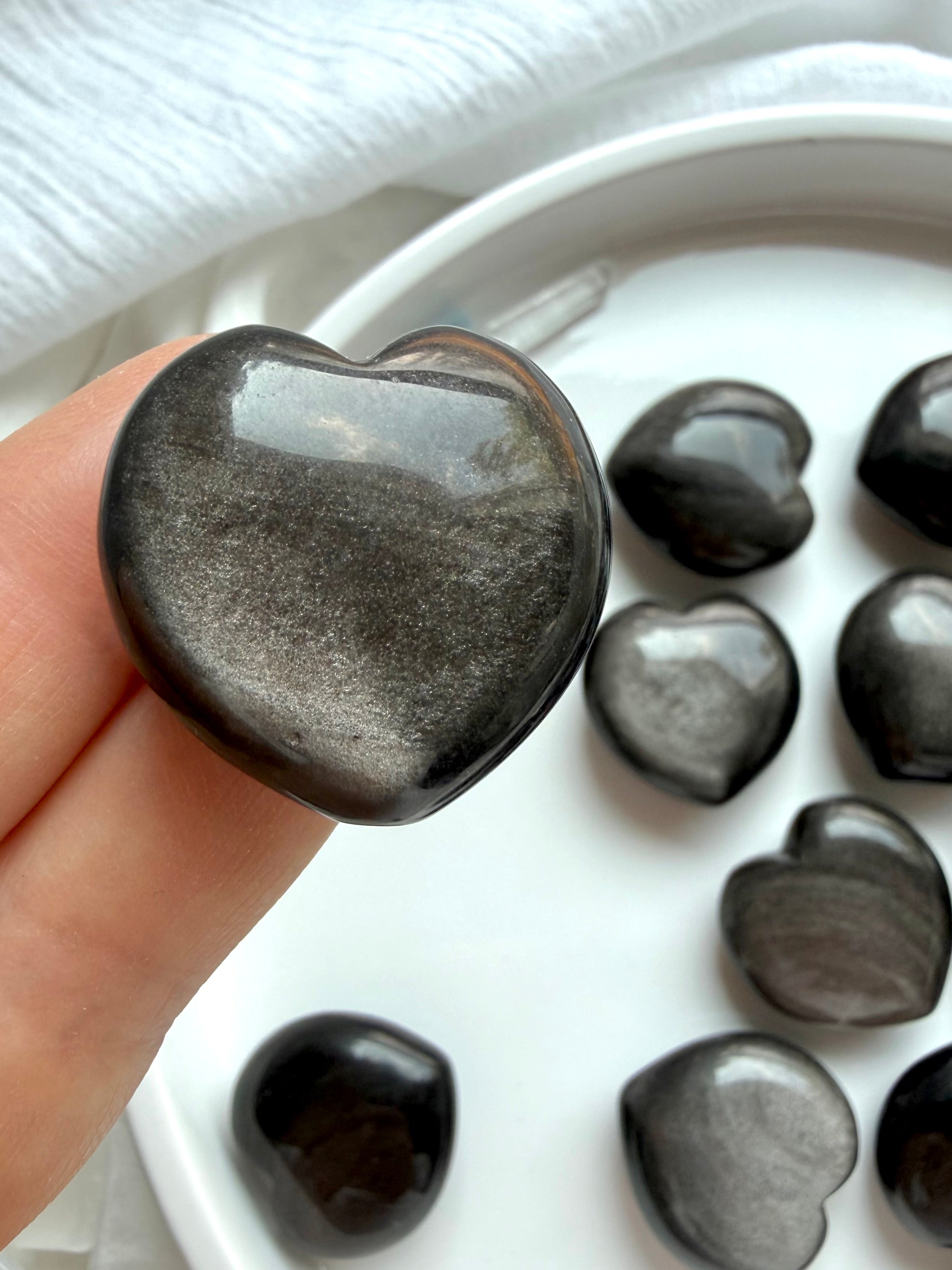 Silver Sheen Obsidian heart held in hand showing smoky charcoal color and reflective silver sheen