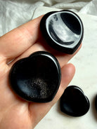 silver sheen obsidian heart worry stone held in hand for protection grounding and emotional clarity