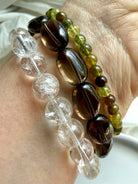Rainbow Quartz, Smoky Quartz, and Tsavorite Garnet bracelet stack with transparent crystal gemstones and earthy neutral tones